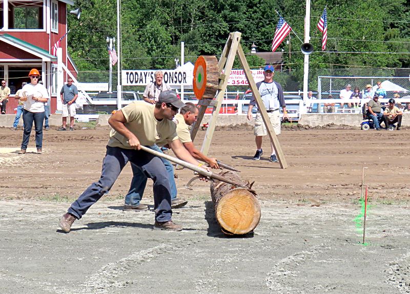 Two lumberjacks use cant hooks to roll a log toward the pins at the Woodsmen's Competition.