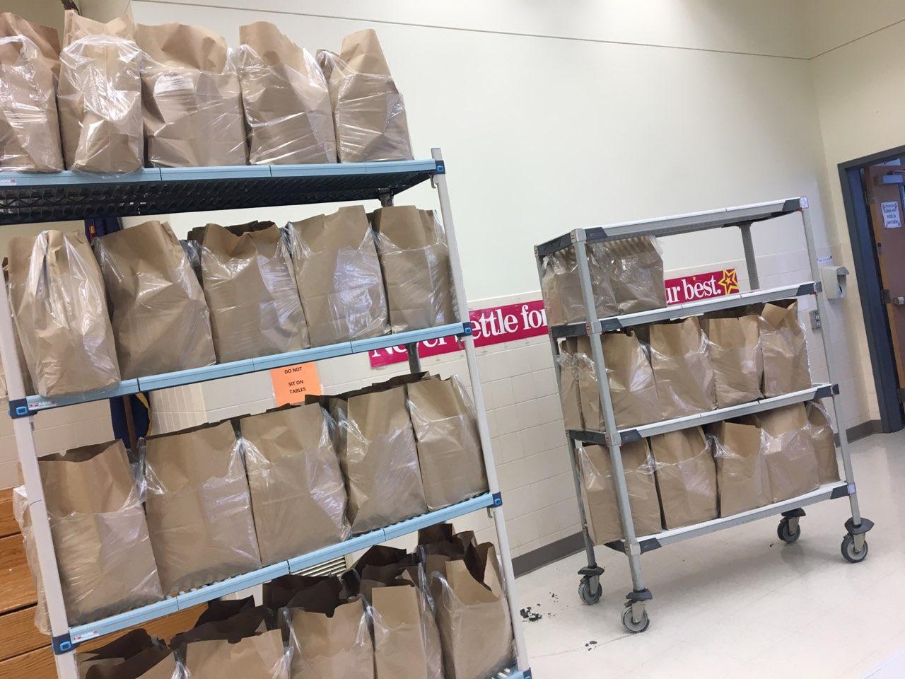 A wheeled cart stacked with bags of food items to be distributed by the Food Pantry Program.